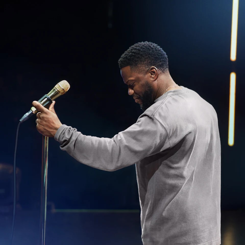 Comedian and actor Kevin Hart posing with a microphone.